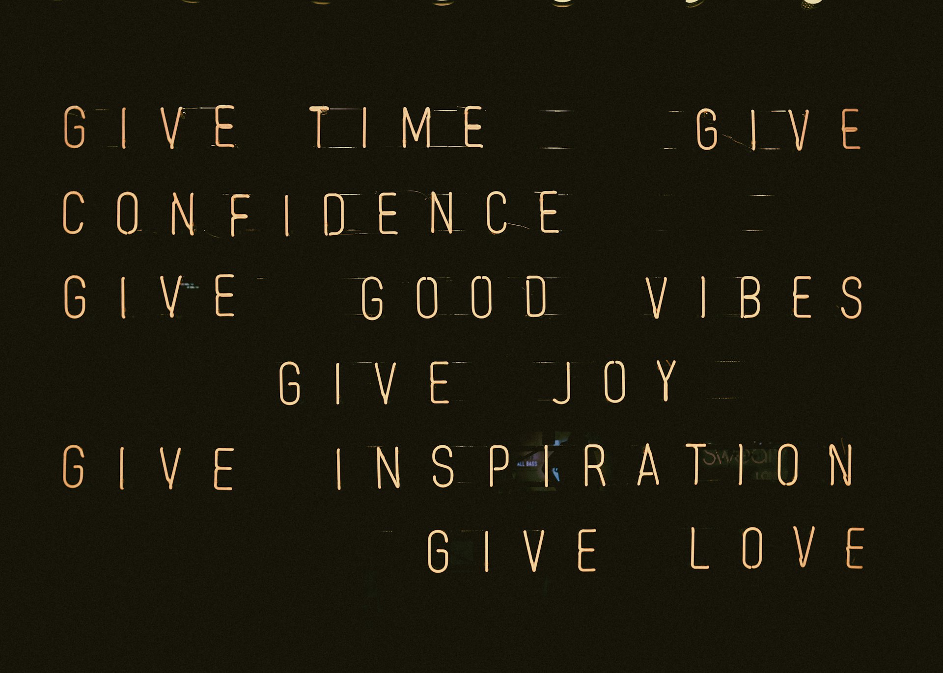 Neon text with the words: Give time, confidence, good vibes, joy, inspiration, and love